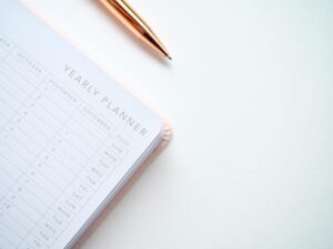 Close-Up-Photo-of-Yearly-Planner-Beside-a-Pen